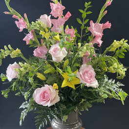 Pink roses and gladiolus in a glass vase with yellow lilies