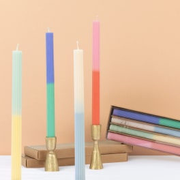 Four ribbed pastel taper candles with gold holders and a boxed set