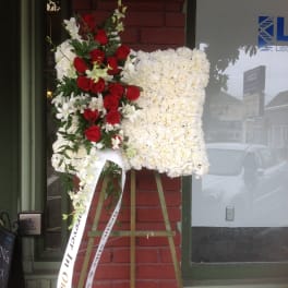 Standing floral easel with red roses and white flowers on a ribboned display