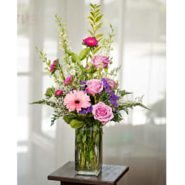 Pink and purple mixed flower arrangement in a clear glass vase