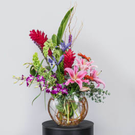 Tall mixed floral arrangement in a round glass vase