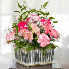 Pink mixed flowers arranged in a clear rectangular vase