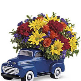 Blue truck figurine filled with colorful flowers