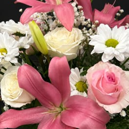 Pink lilies and roses with white daisies in a mixed bouquet