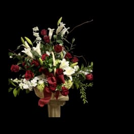 Basket arrangement of red roses and white lilies with a red ribbon