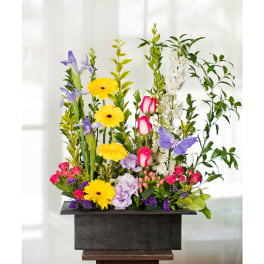 Tall mixed flower arrangement in a dark rectangular container