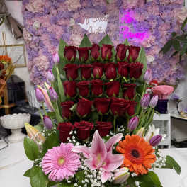 Basket arrangement of red roses with pink lilies and gerbera daisies