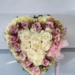 Heart-shaped bouquet of pink and white roses with a pink ribbon