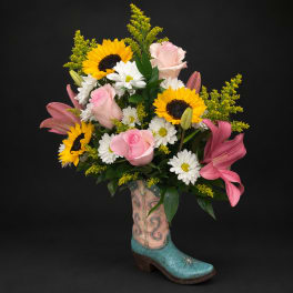 Bouquet of sunflowers, pink roses, white daisies, and lilies in a boot vase