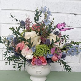 Mixed bouquet in a white face vase with pink, white, and blue flowers