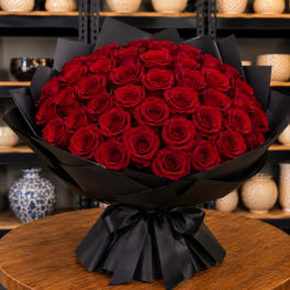 Large bouquet of red roses wrapped in black paper with a black ribbon