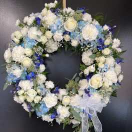 Heart-shaped floral wreath with white and blue flowers and a sheer ribbon