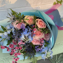 Bouquet of pink roses and blue flowers wrapped in turquoise paper