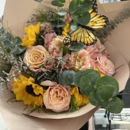 Bouquet of peach roses and sunflowers with a butterfly accent
