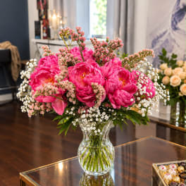 Pink peony bouquet in a clear glass vase with white filler flowers