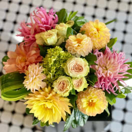 Mixed bouquet of pink, yellow, and peach flowers in a compact arrangement