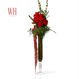 Tall red rose arrangement in a clear glass vase with trailing red flowers
