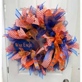 A blue and orange decorative wreath with Auburn War Eagle ribbons on a white door