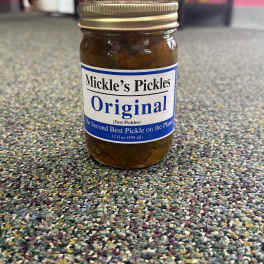 Jar of pickles with a gold lid on a carpeted floor