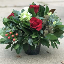 Red roses and pale green blooms in a black container