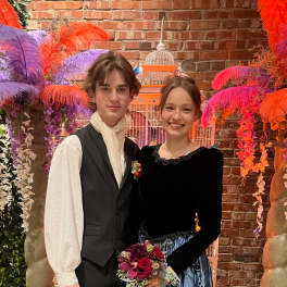 Young couple posing with a small red rose bouquet at a formal event