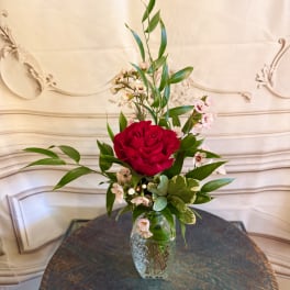 Red rose arrangement in a clear glass vase with small pink accent flowers
