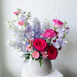 Bouquet of pink roses, lavender blooms, and white flowers in a ribbed vase