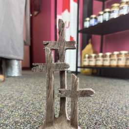 Three rustic wooden cross decorations on a carpeted floor