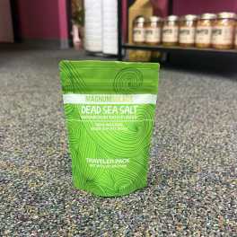 Green pouch of Dead Sea salt bath flakes on a carpeted floor