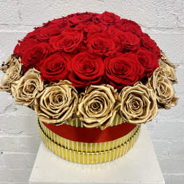 Round arrangement of red and gold roses in a striped box