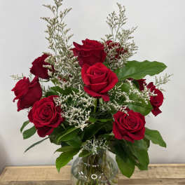 Red roses arranged in a clear glass vase with white filler flowers