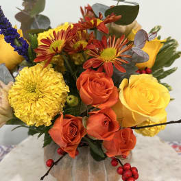 Bouquet of yellow and orange roses with chrysanthemums in a pumpkin vase
