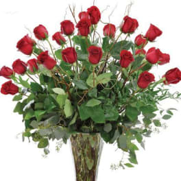 Tall vase arrangement of red roses with greenery