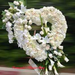 Large white heart-shaped standing wreath with roses, lilies, orchids, and calla lilies