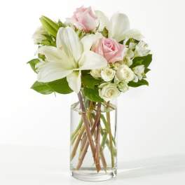 Bouquet of white lilies and pale pink roses in a clear glass vase