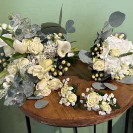 White rose and calla lily bouquets with eucalyptus on a table