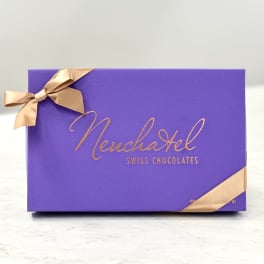 Purple box of Neuchatel Swiss chocolates tied with gold ribbon