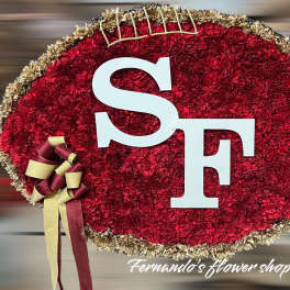 Football-shaped red carnation floral display with white SF letters and gold and burgundy ribbon.