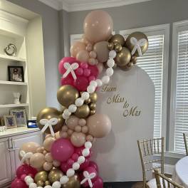 Pink, gold, and white balloon arch around a "From Miss to Mrs" sign