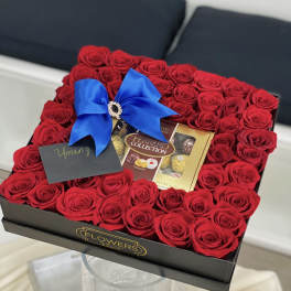 Box of red roses with a blue bow and chocolates