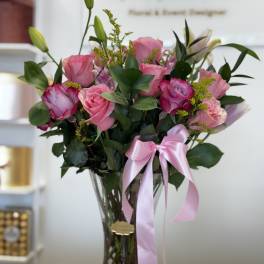 Pink roses in a clear glass vase with a pink ribbon