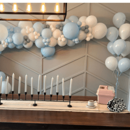 Blue and white balloon garland above a table with candles