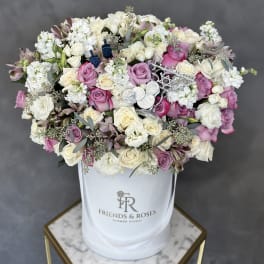 Pink and white roses arranged in a white hat box