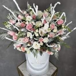 Pink and white roses in a white hatbox with frosted winter accents