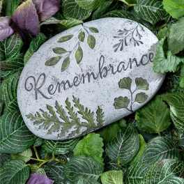 Decorative remembrance stone surrounded by green and purple foliage