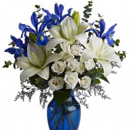 White lilies and roses with blue irises in a blue vase