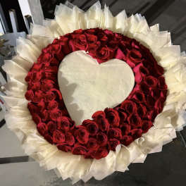 Heart-shaped arrangement of red roses with white wrapping around it