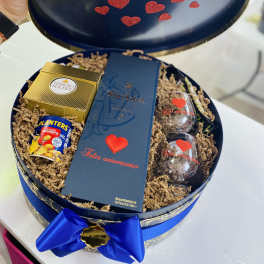 Gift box with chocolates, peanuts, and two glasses inside a round blue case