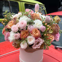 Pastel bouquet of roses, tulips, and carnations in a pink hat box