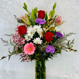 Mixed bouquet of roses, lilies, daisies, and carnations in a glass vase